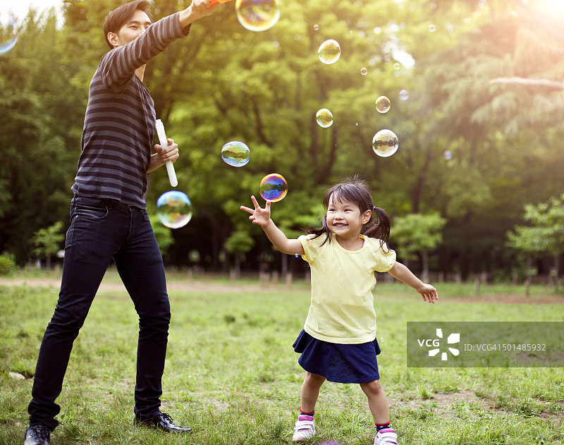 父女在公园里玩肥皂泡泡图片素材