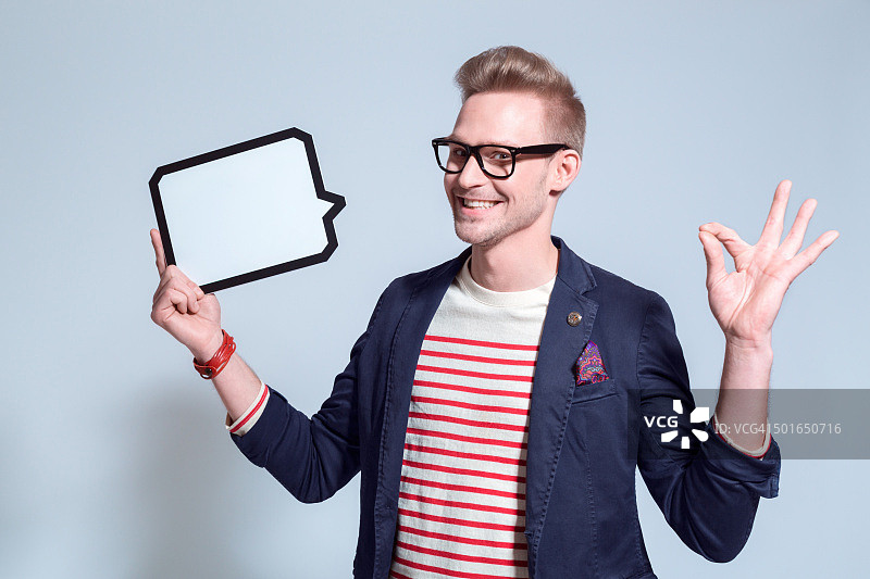 拿着语音气泡的兴奋金发年轻男人图片素材