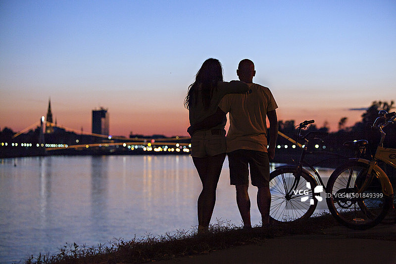 克罗地亚奥西耶克：夜晚骑自行车看城市的年轻夫妇图片素材