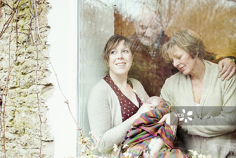 母亲和宝宝与祖父母在窗边图片素材