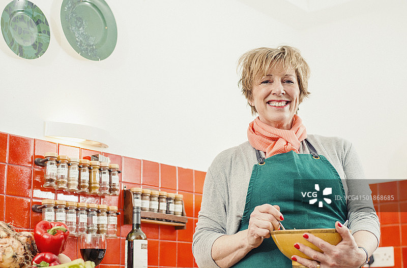 在厨房里拿着搅拌碗的中年妇女图片素材