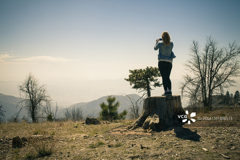 中年妇女在树干后摄影，美国加利福尼亚州箭头湖图片素材