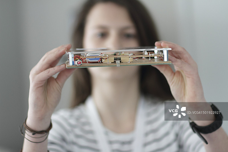 年轻女人在电子车间里拿着光学传感器图片素材