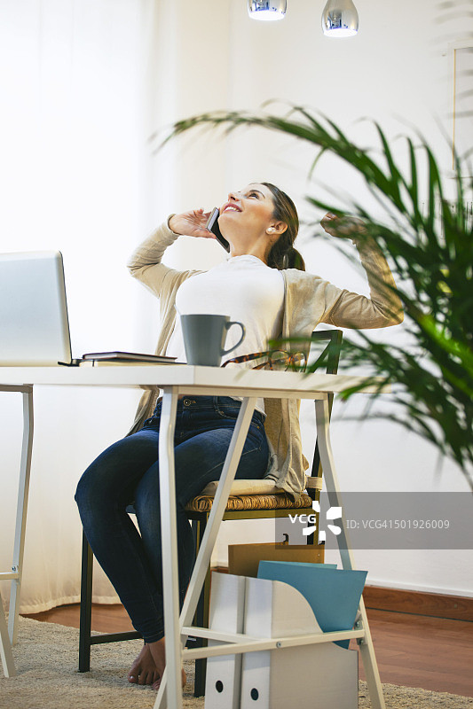 在现代家庭办公室用智能手机打电话的女人肖像图片素材