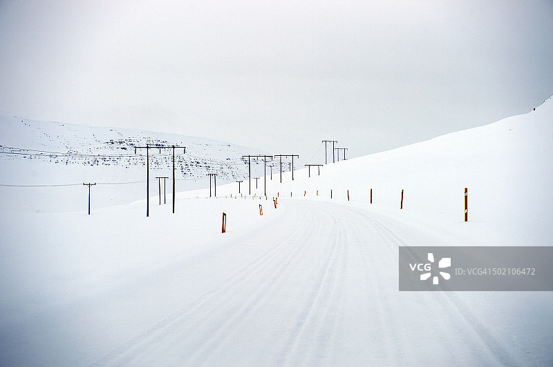 冰岛西峡湾区迪拉峡湾的电气线路和积雪覆盖的道路图片素材