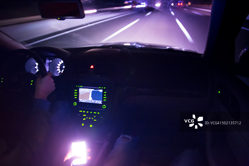 夜晚在高速公路上行驶并查看明亮的智能手机屏幕图片素材