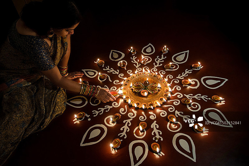 排灯节期间点亮油灯的年轻女子图片素材