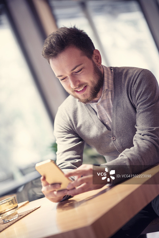在咖啡店使用智能手机的年轻英俊男子图片素材