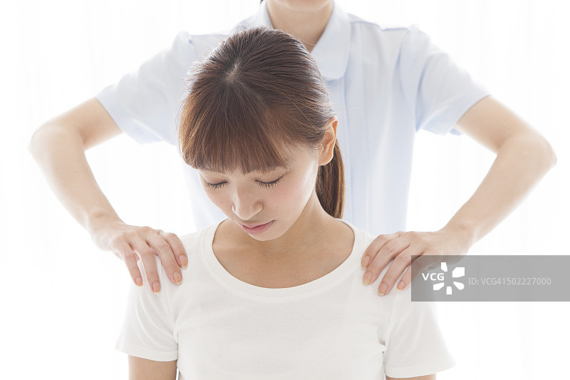 女性接受按摩师的肩部按摩图片素材