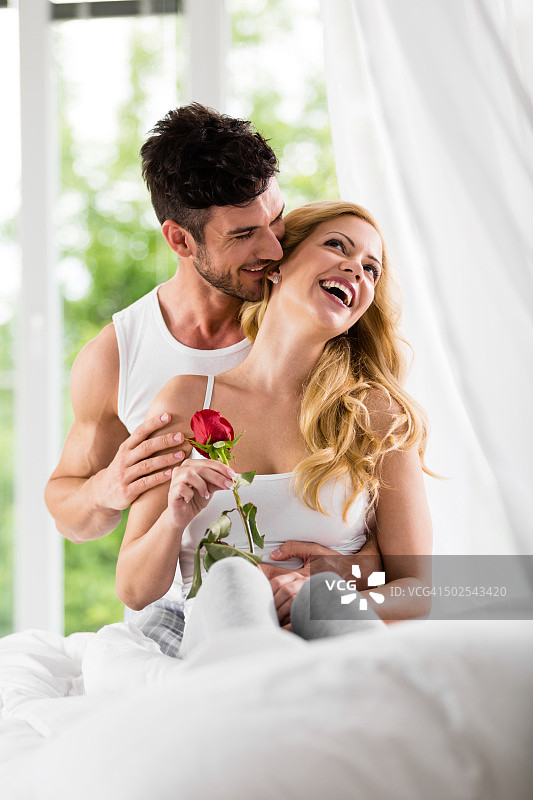 情侣在床上拿着玫瑰嬉戏图片素材