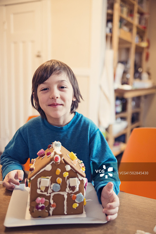 自豪的男孩展示自制姜饼屋图片素材