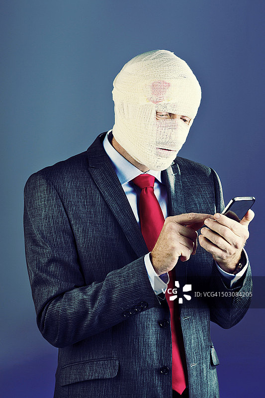 头部缠着绷带，忙着发短信的商人图片素材