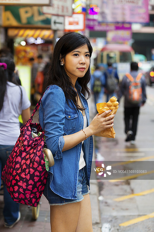 年轻的亚洲女人吃鸡蛋仔图片素材