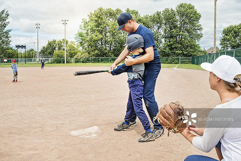 妈妈、爸爸和他们的三个儿子在夏天打棒球图片素材