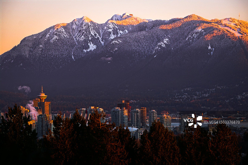 温哥华市中心天际线与日出时白雪皑皑的山脉图片素材