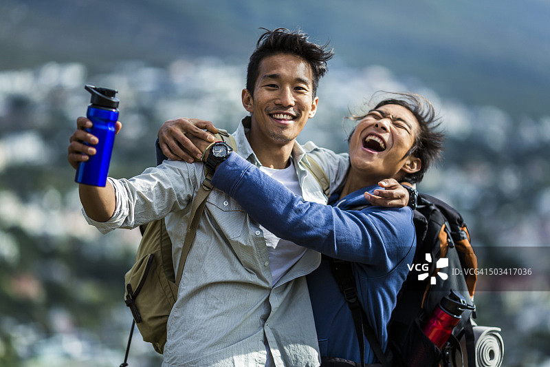 快乐的徒步旅行者在山丘上拥抱朋友图片素材