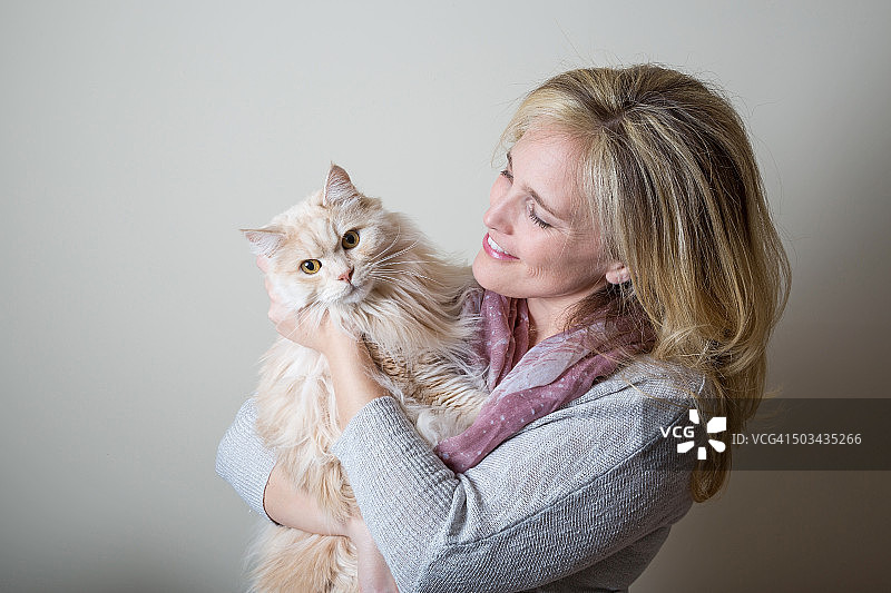 漂亮的白人金发女人看着漂亮的白猫图片素材