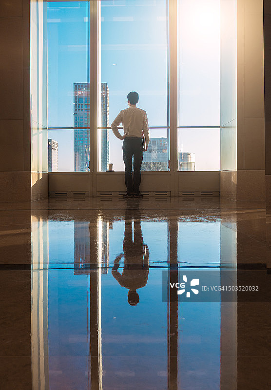 商务人士在窗边眺望城市图片素材