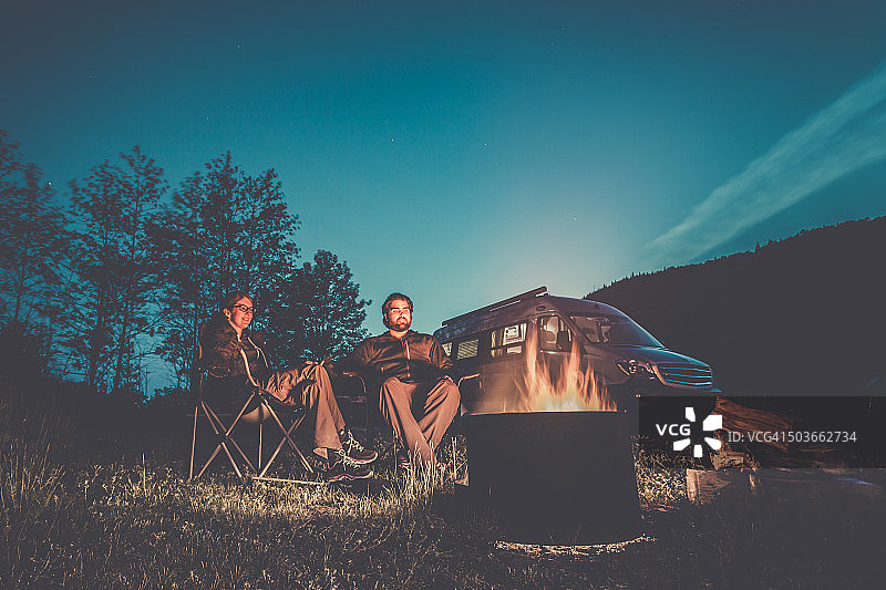 情侣坐在露营车旁的篝火旁图片素材