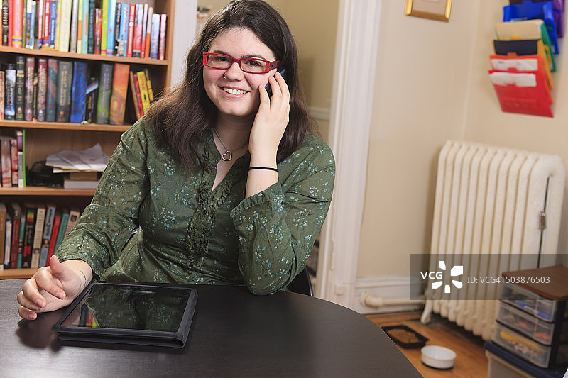 在家用智能手机和平板电脑工作的阿斯伯格综合征女人图片素材