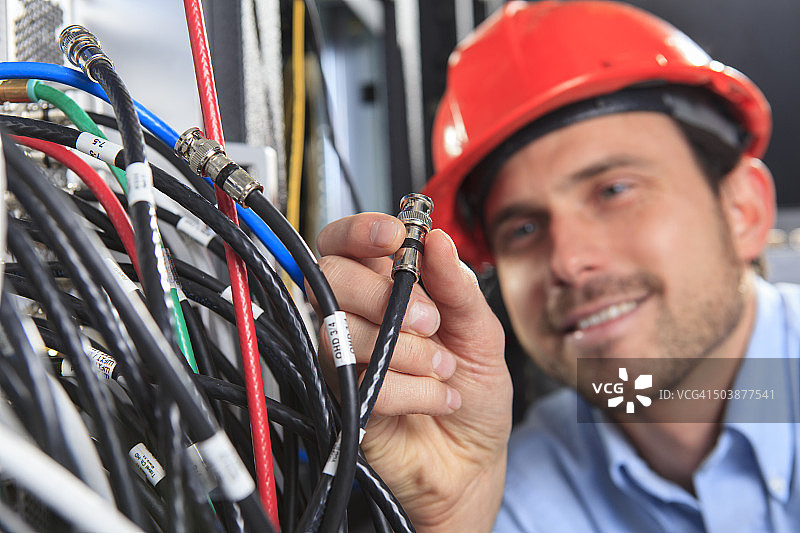 手持BNC线缆连接配线架的网络工程师图片素材