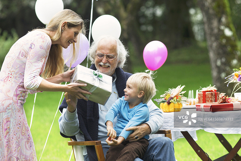 爷爷在花园生日派对上收到礼物图片素材