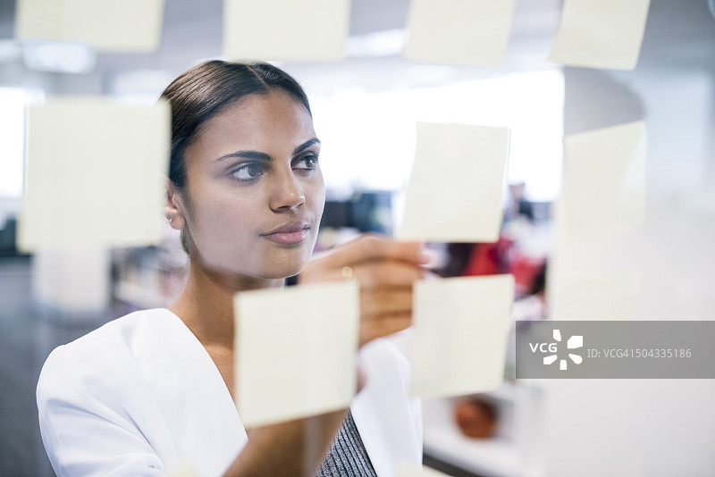 女商人往窗户上贴便条，进行业务规划图片素材