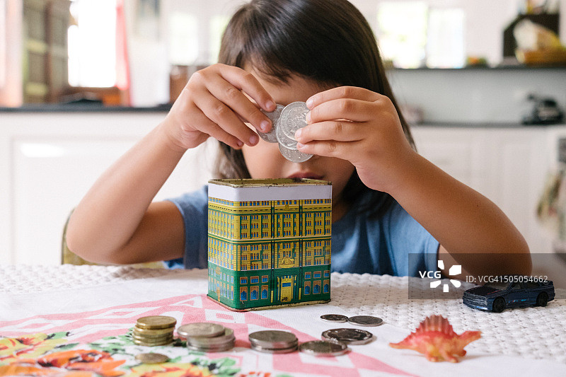 孩子用澳大利亚货币在存钱罐里存钱图片素材