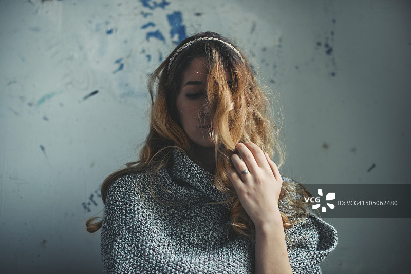 年轻女人站在墙前，面带忧伤图片素材