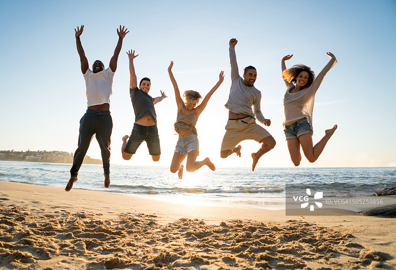 一群朋友在海滩跳跃图片素材