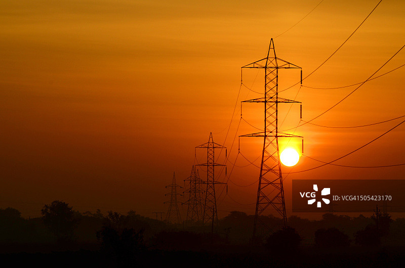 日出光芒下的电线杆和电线，古吉拉特邦，印度图片素材