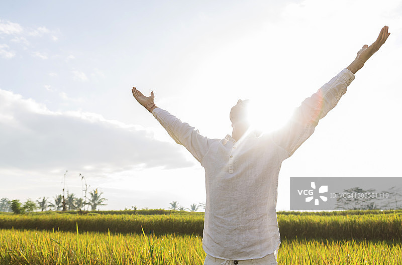 在晨光中伸展双臂的年轻白人胡须男子图片素材