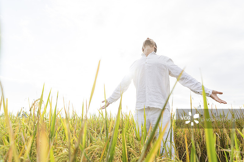 在晨光中伸展双臂的年轻白人胡须男子图片素材