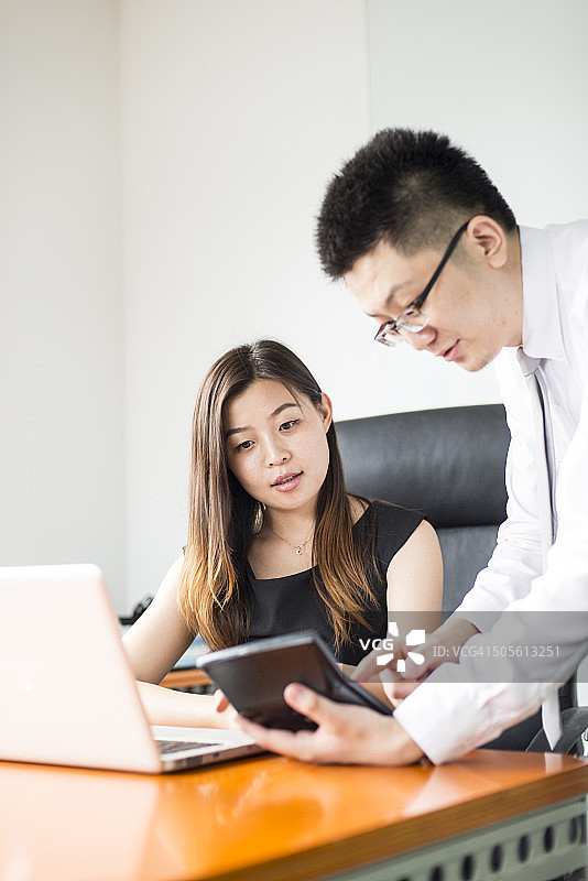 使用计算器的商务人士进行讨论图片素材