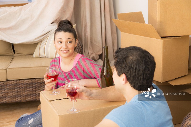 搬家：拉丁夫妇喝着葡萄酒，新家，乔迁，打开箱子图片素材