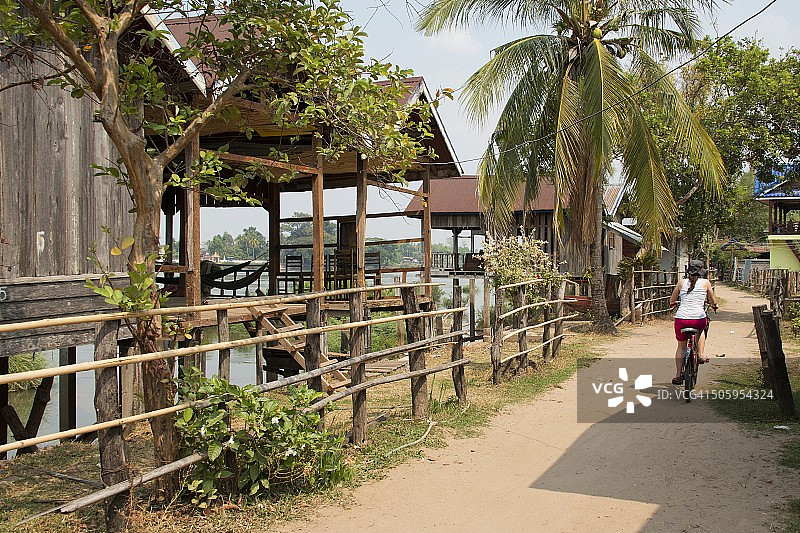 女游客在老挝东德岛湄公河畔骑行的背影图片素材
