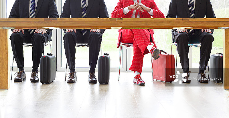 四名男子坐在桌旁，一人身穿红色西装图片素材