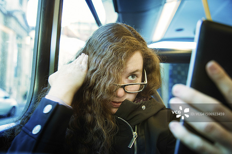 女人在公共汽车上使用平板手机当镜子图片素材