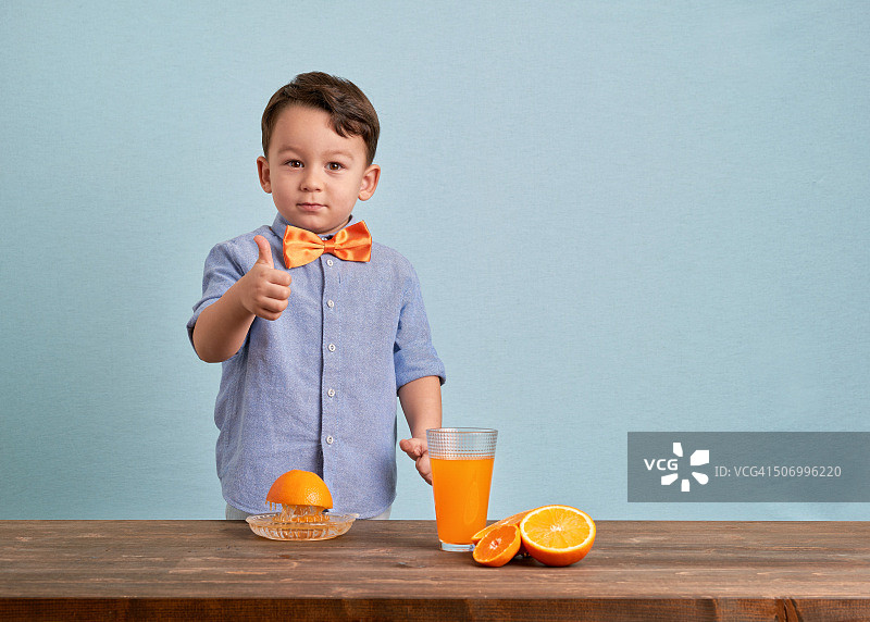 小朋友在准备新鲜橙汁时竖起大拇指图片素材