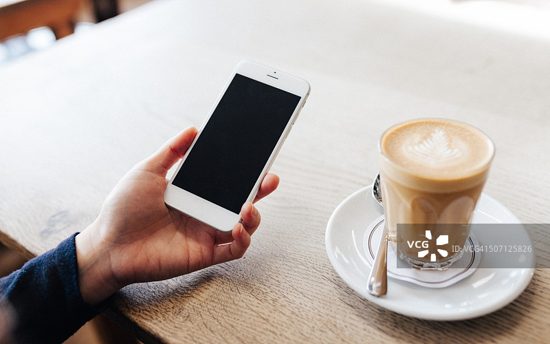 手持咖啡和智能手机的特写图片素材