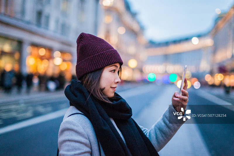 在商业街上拍照的年轻亚洲女士图片素材