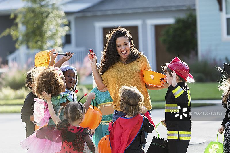 万圣节，女人给一群孩子分发糖果图片素材