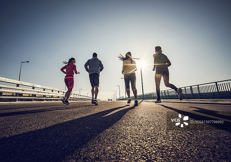 在桥上慢跑的运动员群体的后视图图片素材