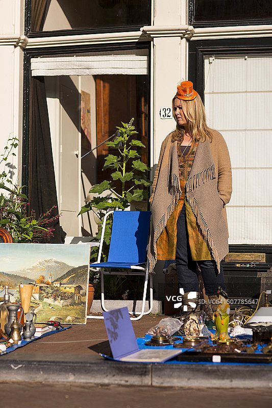 戴橙色帽子的女人在跳蚤市场摊位图片素材