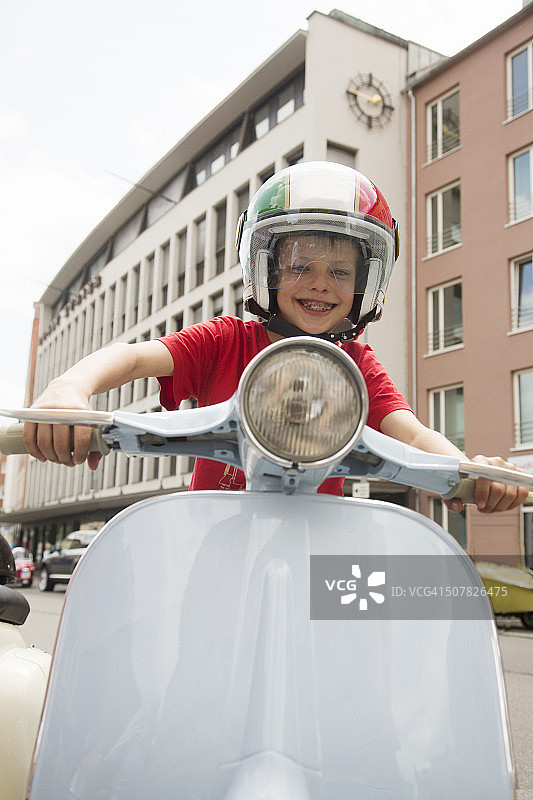 在城市街道上假装骑摩托车的十岁男孩肖像图片素材