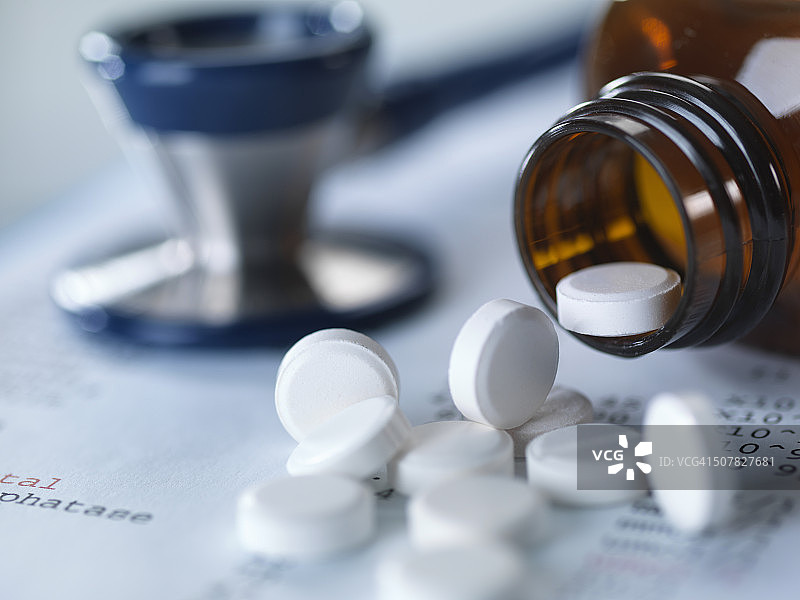 止痛药倒在医疗报告上与听诊器特写图片素材