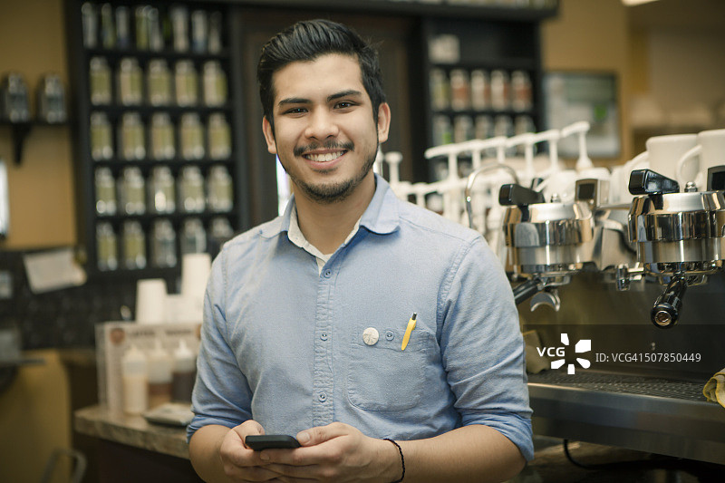 咖啡馆里使用智能手机的咖啡师肖像图片素材
