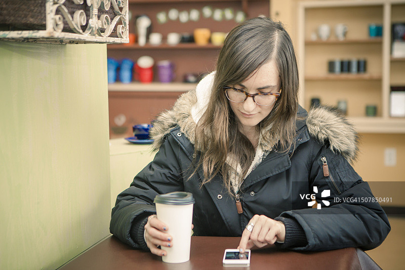 中年妇女在咖啡馆用智能手机发短信图片素材