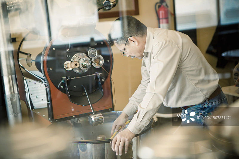在咖啡馆使用咖啡烘焙机的成熟男人图片素材