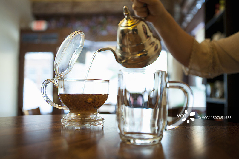 女人手在咖啡馆柜台上倒茶图片素材